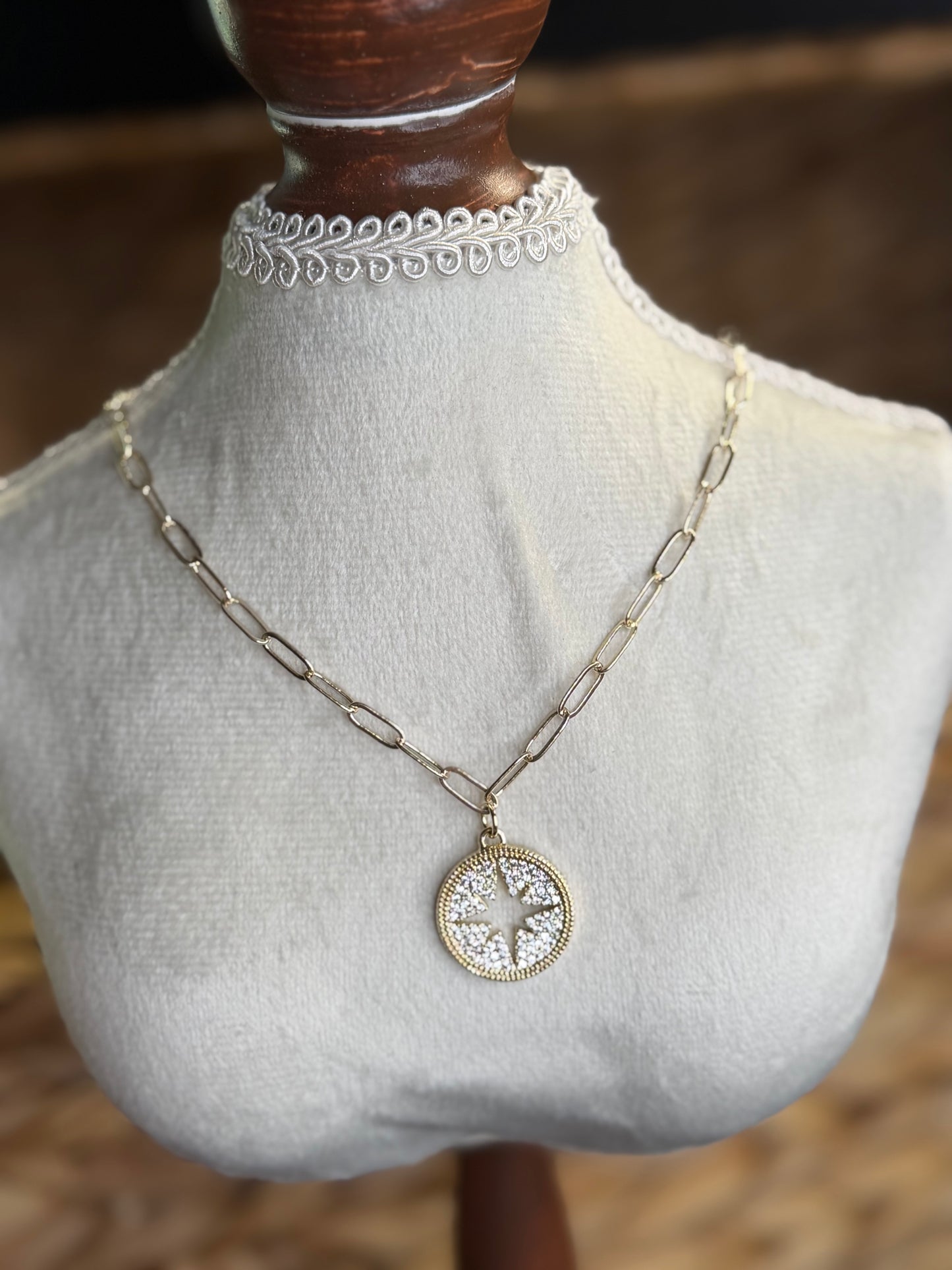 Gold paperclip necklace with star and directions symbol