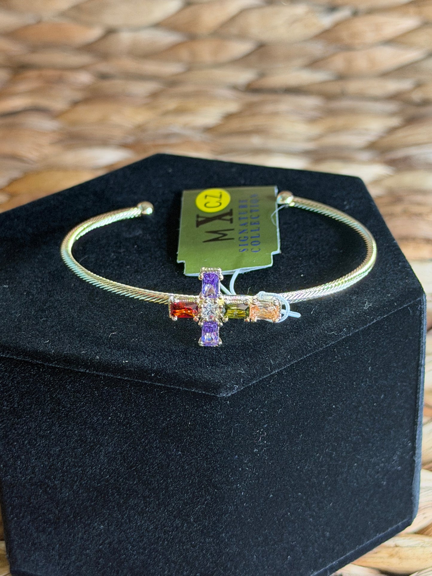 Gold cuff bracelet with colored stones on a Cross
